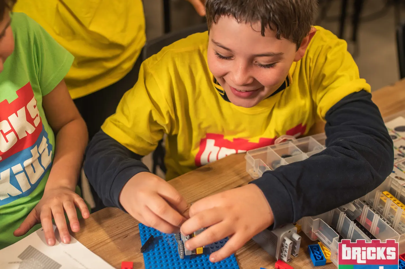 Mani di bambini che assemblano un modello LEGO con ingranaggi durante un laboratorio STEM Bricks 4 Kidz