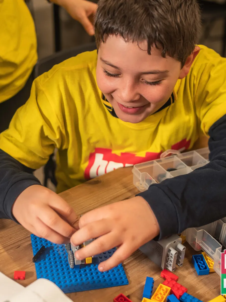 Mani di bambini che assemblano un modello LEGO con ingranaggi durante un laboratorio STEM Bricks 4 Kidz