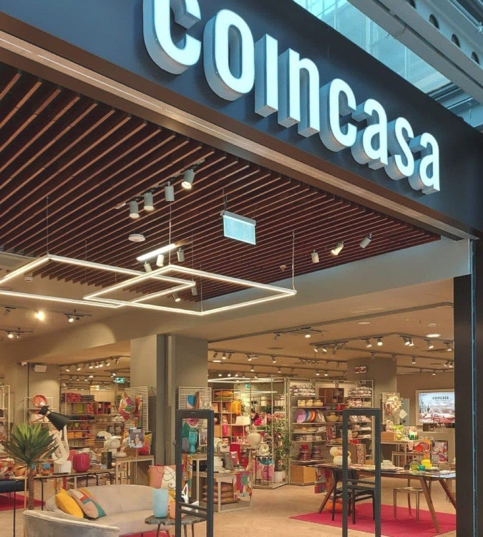 Ingresso di un negozio Coincasa in un centro commerciale, con insegna luminosa e allestimento living in vetrina