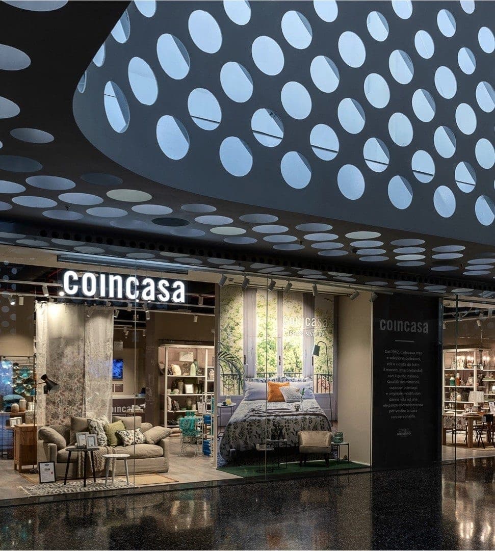 Vetrina di un negozio Coincasa in galleria commerciale, con allestimento camera da letto e zona living