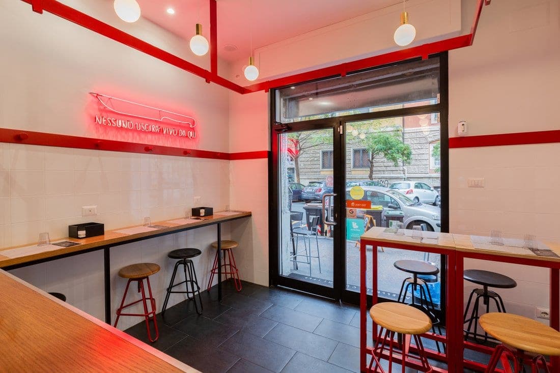 Ingresso di un punto vendita Cucchi Burgers a Roma con insegna al neon Nessuno uscirà vivo da qui