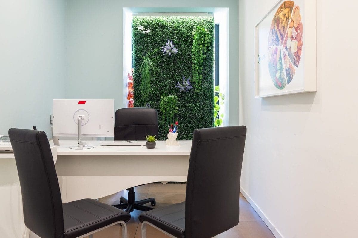 Sala consulenze di un centro Diètnatural con scrivania, monitor e parete verde