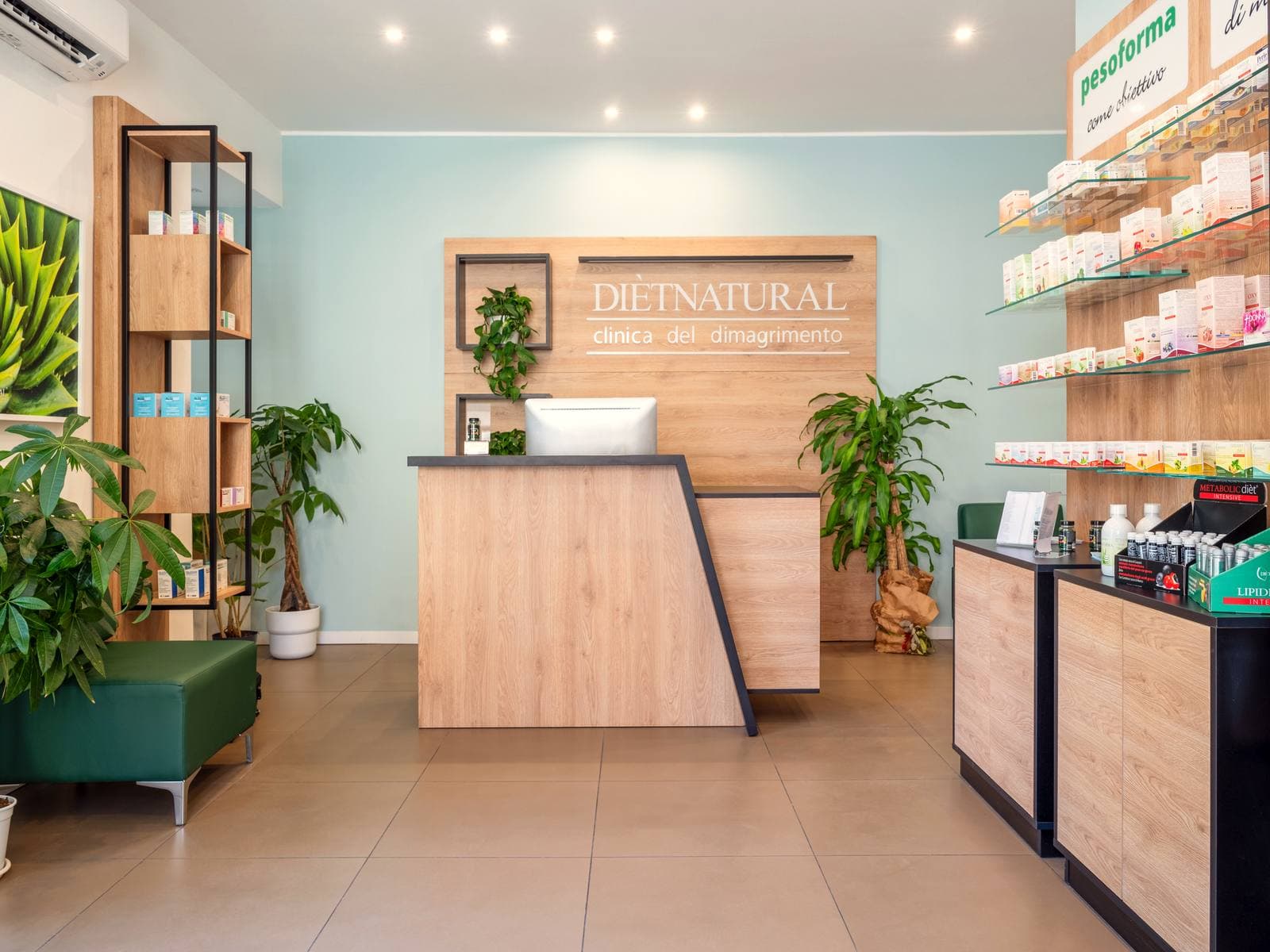 Interno di un centro Diètnatural: reception con l'insegna «clinica del dimagrimento», pareti di prodotti in rovere, piante e area d'attesa