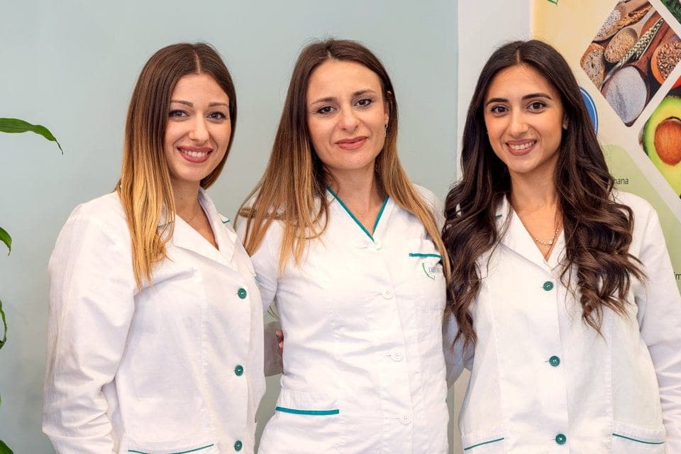 Tre consulenti Diètnatural sorridenti nella divisa bianca col marchio, in un centro della rete