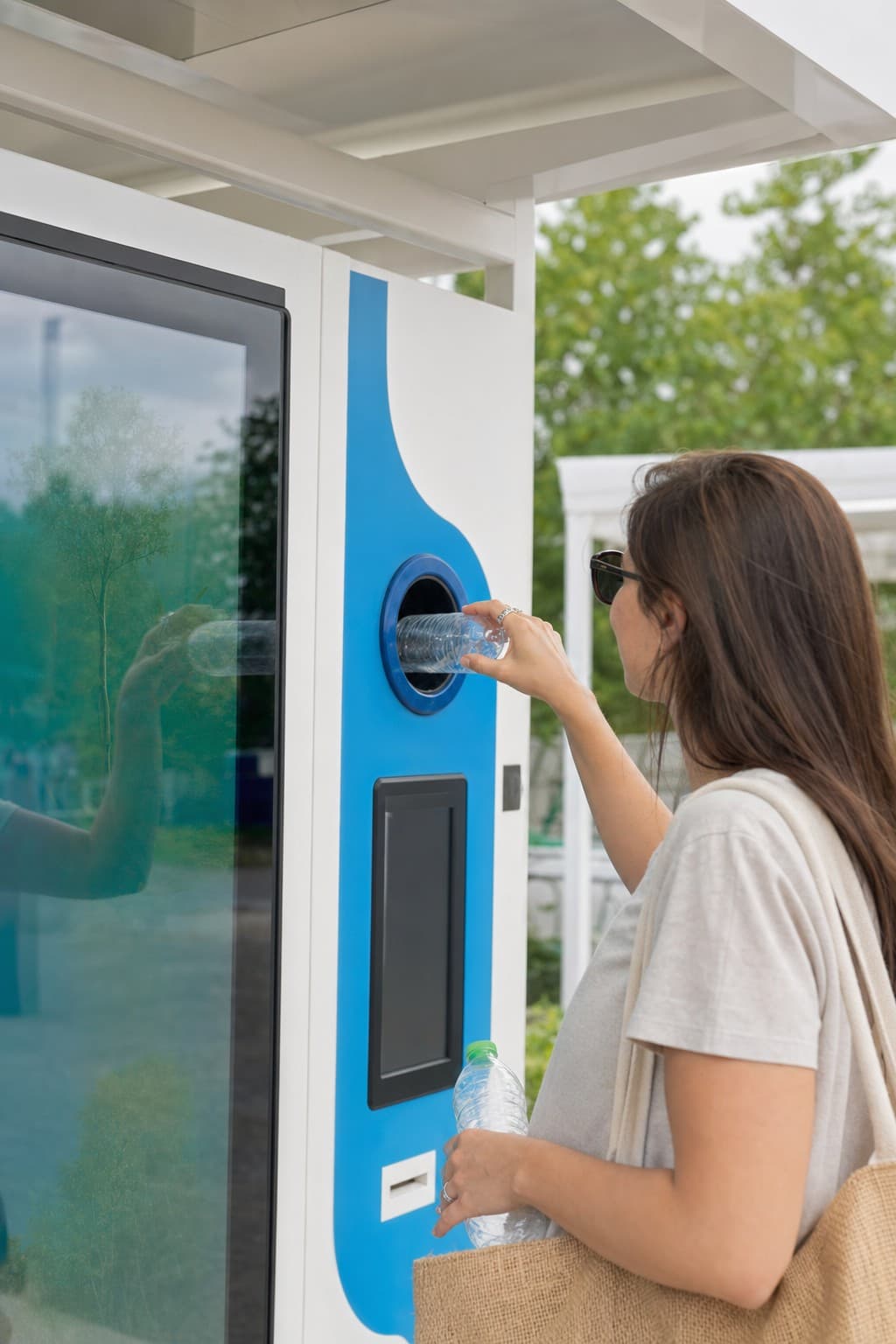 Mani che riciclano una bottiglia in un eco-compattatore Ecoreversa