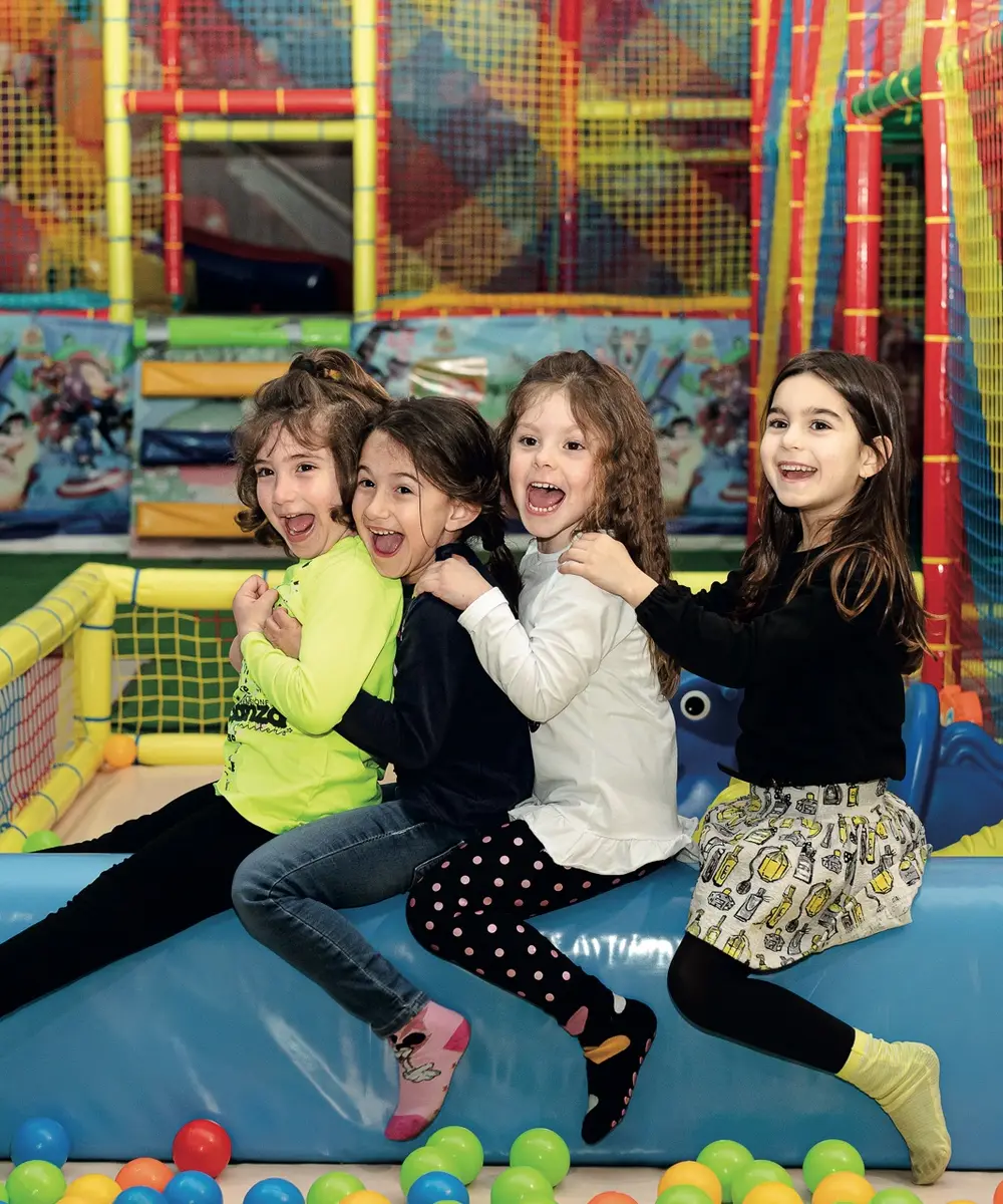 Bambine che ridono sul bordo della vasca palline nel family park Il Ruggito del Coniglio