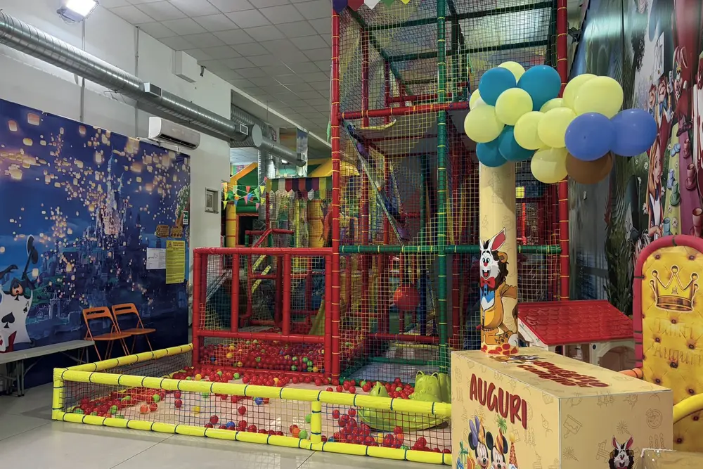 Area feste con palloncini, trono e scatola degli auguri accanto al playground