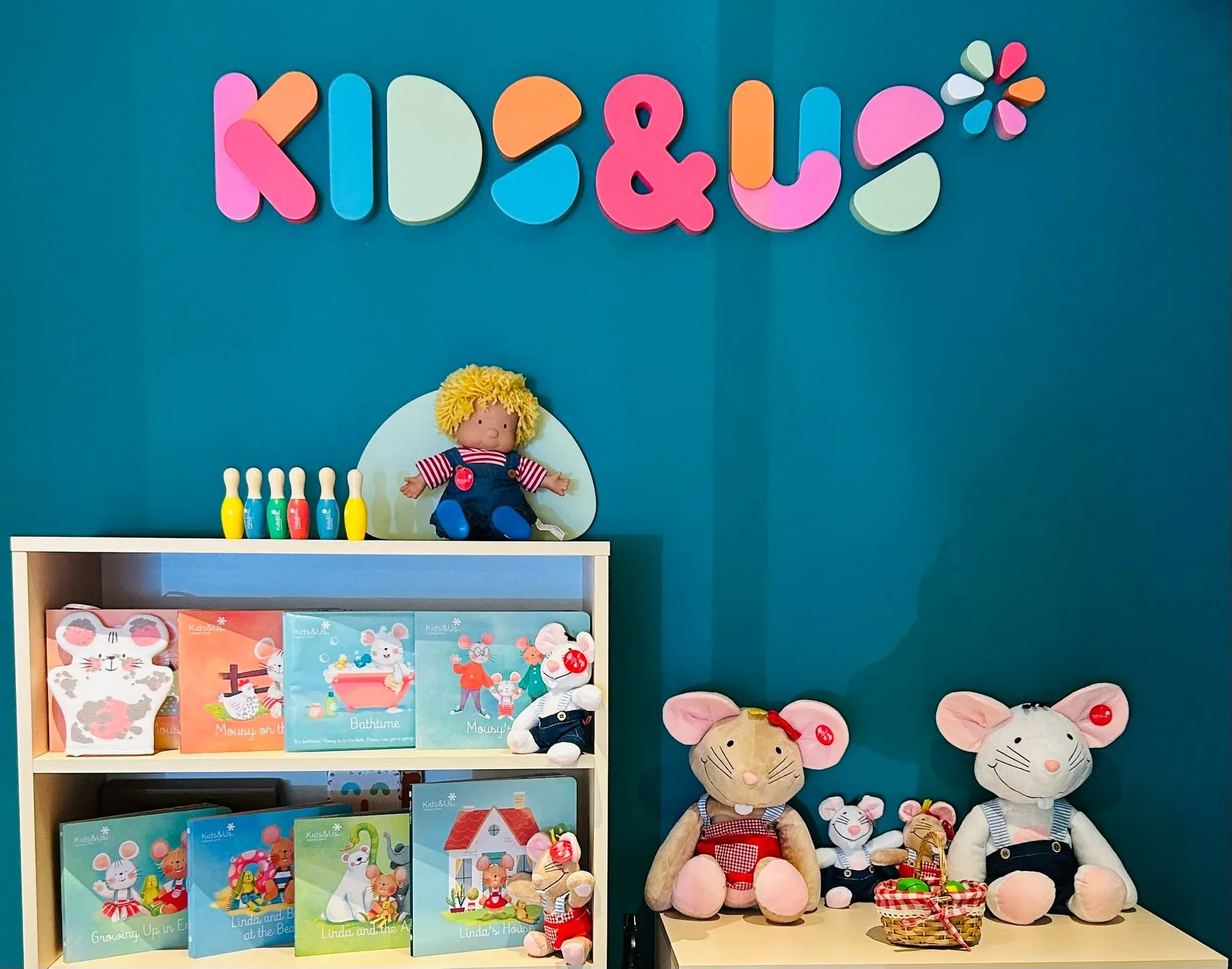 La parete con il logo Kids&Us, i libri e i pupazzi del metodo in una scuola della rete