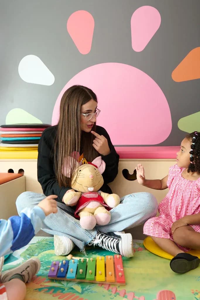 Un'insegnante Kids&Us parla in inglese a un gruppo di bambini piccoli seduti sul tappeto
