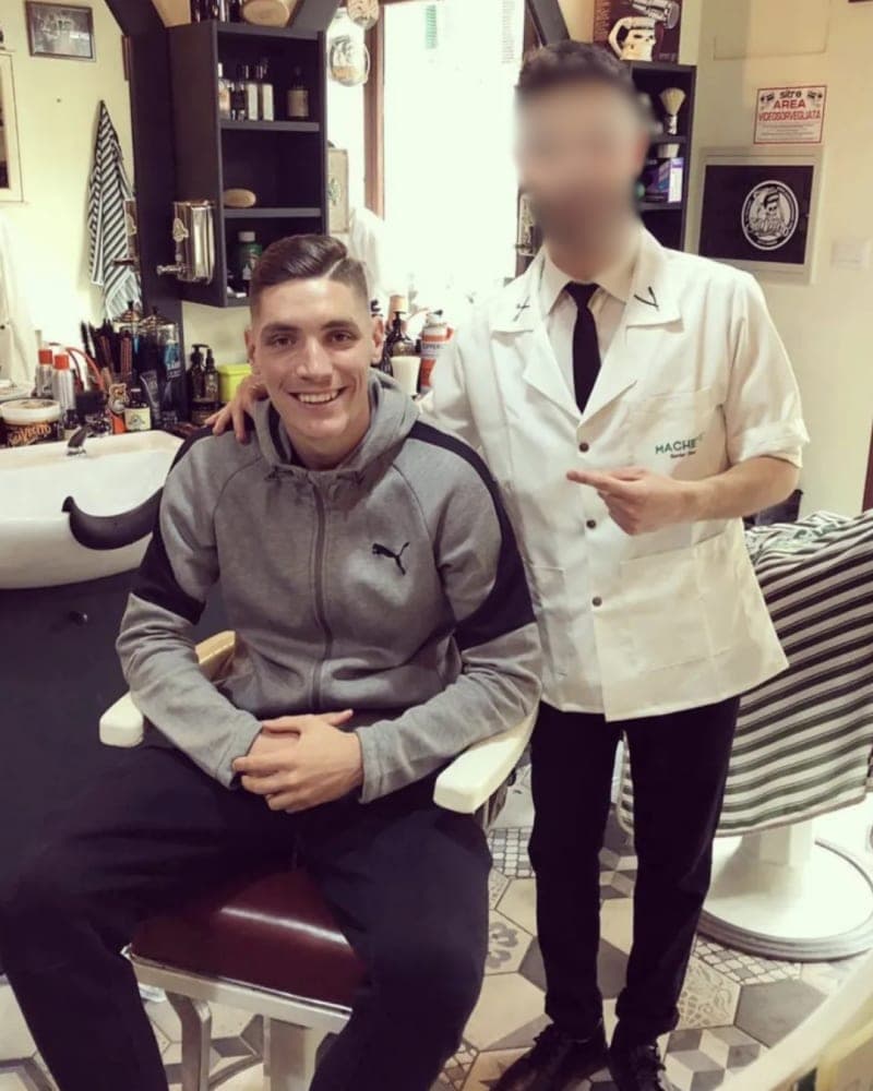 Interno di un salone Machete Capelli & Barba con barbiere e cliente