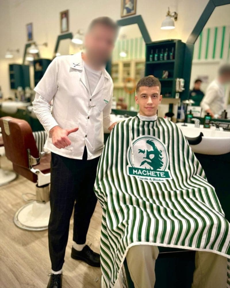 Cliente Machete con il mantello del brand nel salone Capelli & Barba