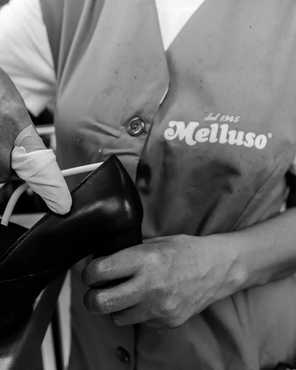Un'operaia Melluso rifinisce a mano una scarpa in pelle, con il grembiule «dal 1945 Melluso»
