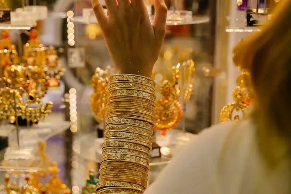 Cliente con i bracciali d'oro davanti alla vetrina di una gioielleria