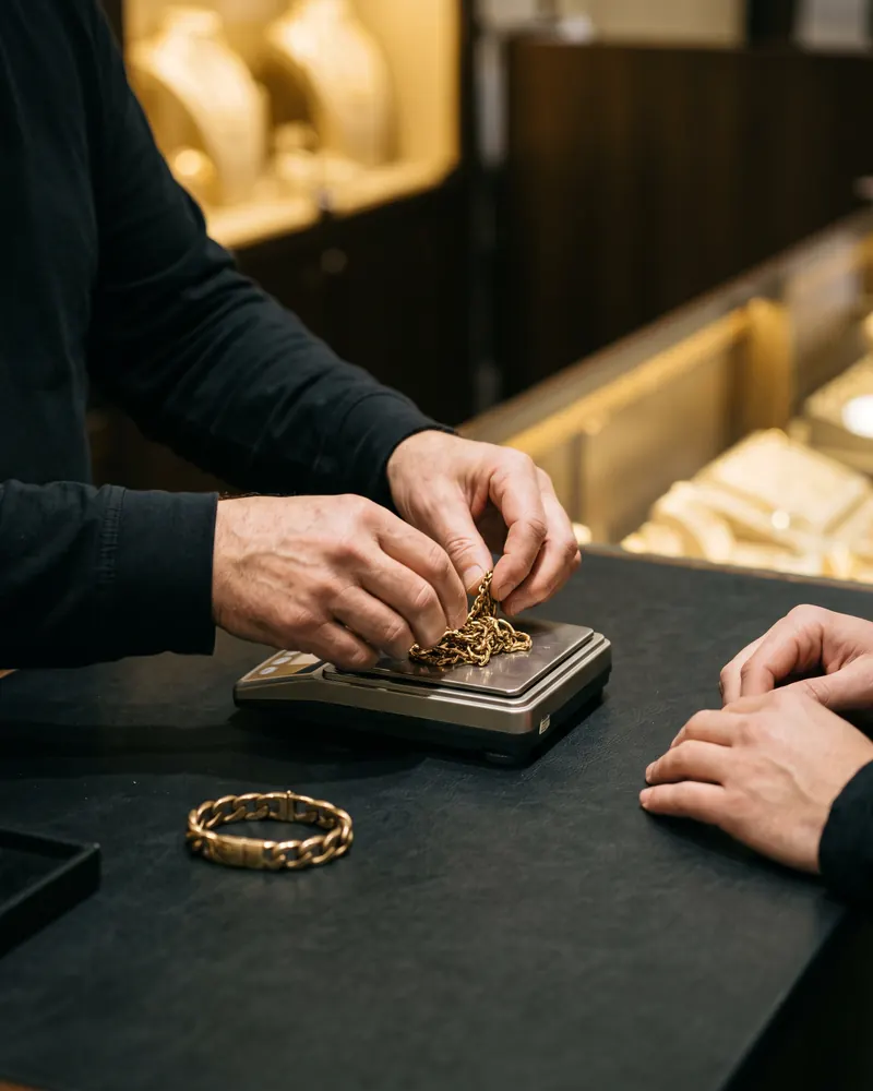Operatore che pesa una catena d'oro sul bilancino, davanti al cliente