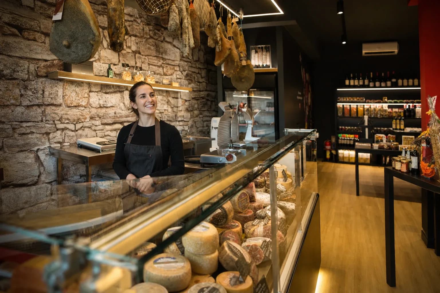 Bottega Quintovizio con banco di salumi e formaggi toscani e scaffali di vini