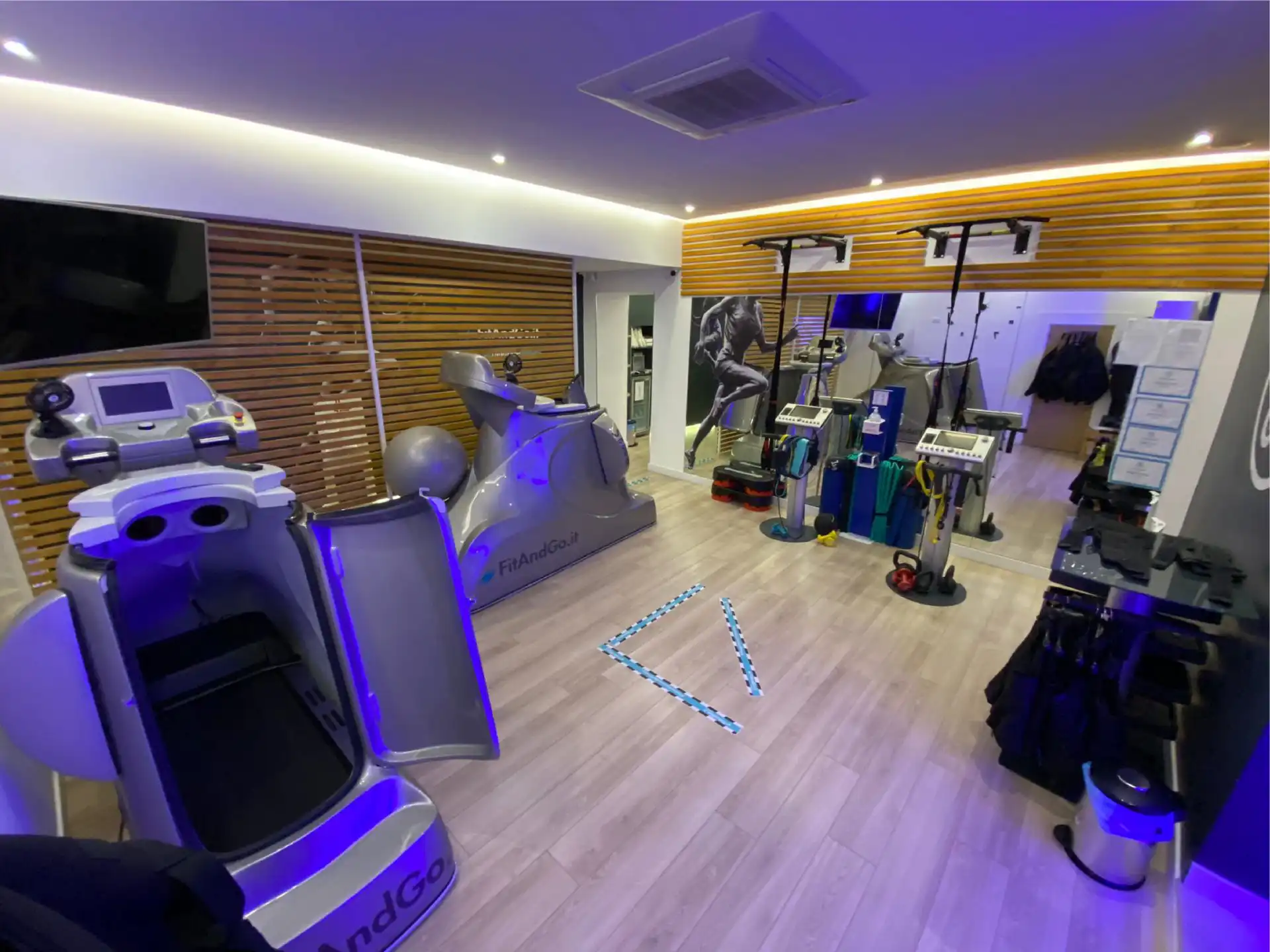 Interno di un centro FitAndGo reale con postazioni EMS, tappeti Vacufit e illuminazione firmata